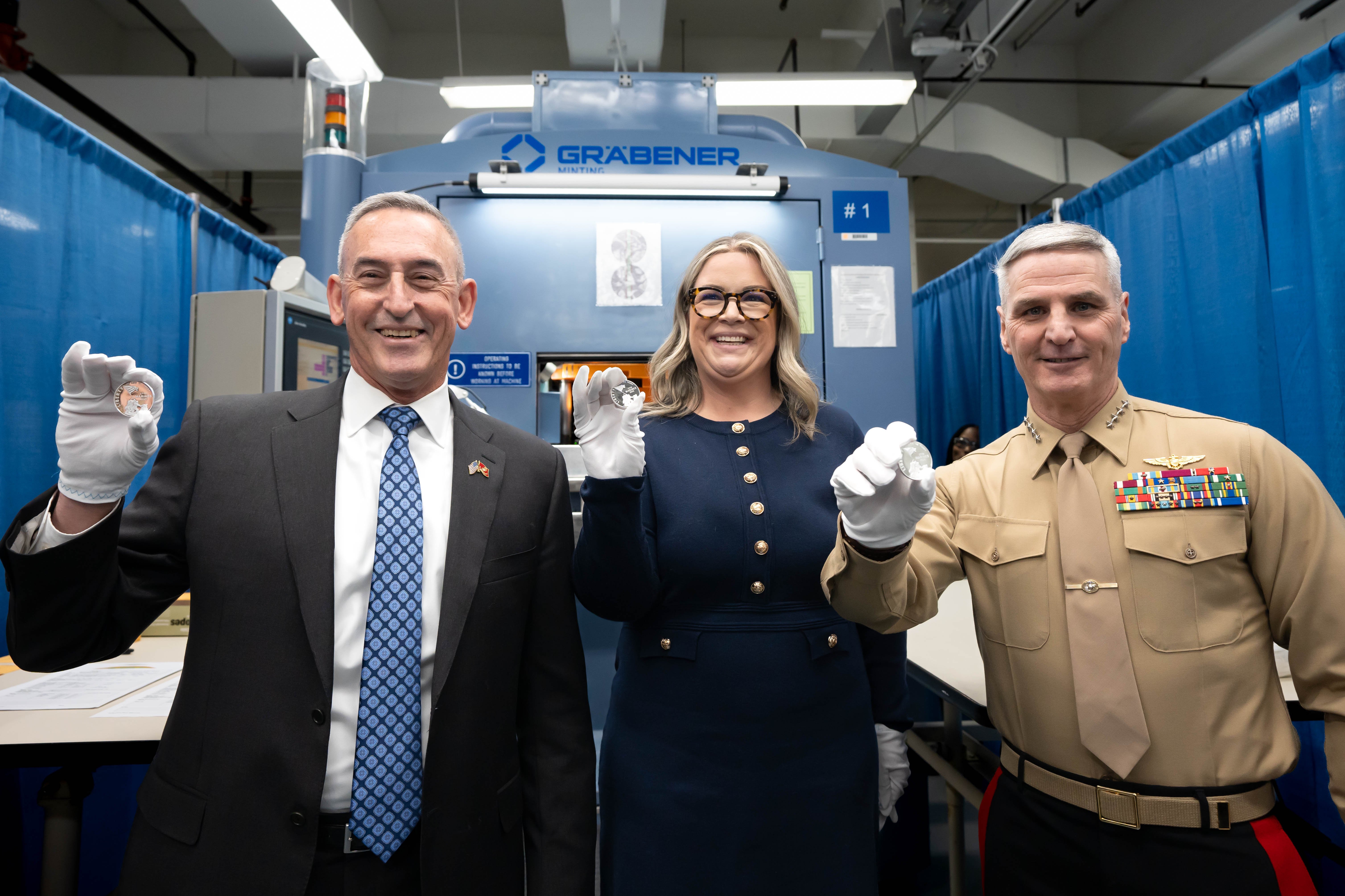MajGen James Lukeman, President and CEO of the Marine Corps Heritage Foundation, Kristie McNally, Deputy Director of the Marine Corps Heritage Foundation, and General Christopher Mahoney, Assistant Commandant of the Marine Corps, showcase the first set of freshly minted Marine Corps 250th Anniversary Commemorative Coins